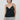 A model wearing a black lace camisole top with thin straps and light manta cargo pants