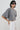 a gray cropped t-shirt with wide, voluminous sleeves and white pants, styled with black sunglasses against a plain light gray background.