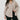 Woman wearing a beige shirt over a black top against a white background