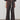 A model wearing a matching dark brown two-piece outfit consisting of a short-sleeve button-front top and wide-leg trousers with a cream drawstring, paired with dark loafers against a minimalist studio background.